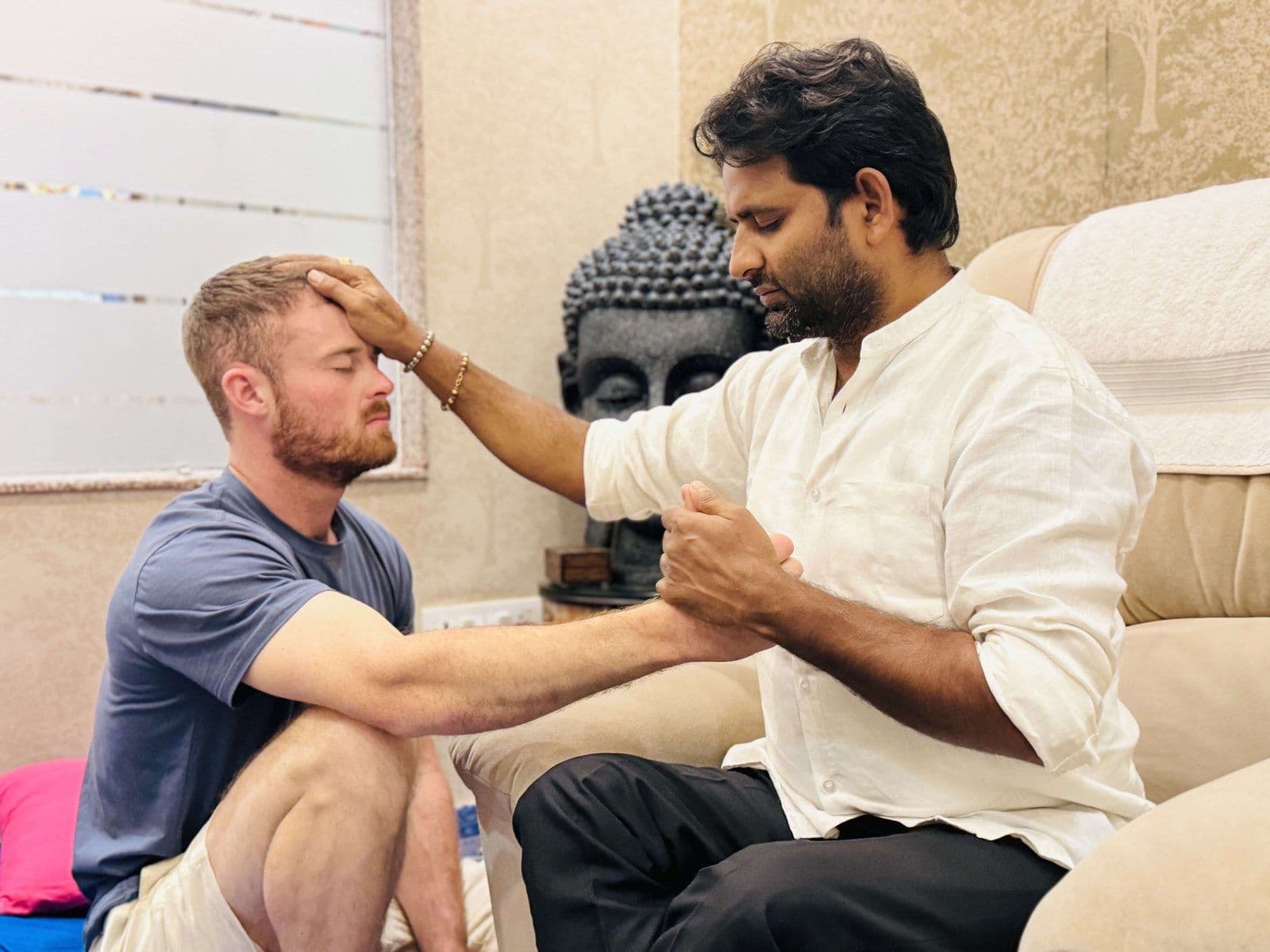 Dr. D.P. Shukla placing a hand on a young man’s forehead during a session