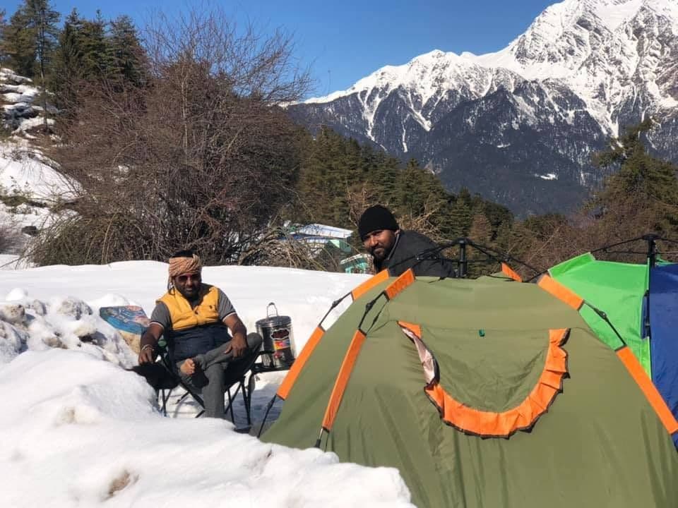 Dr. D.P. Shukla at a snowy campsite with tents and mountain peaks