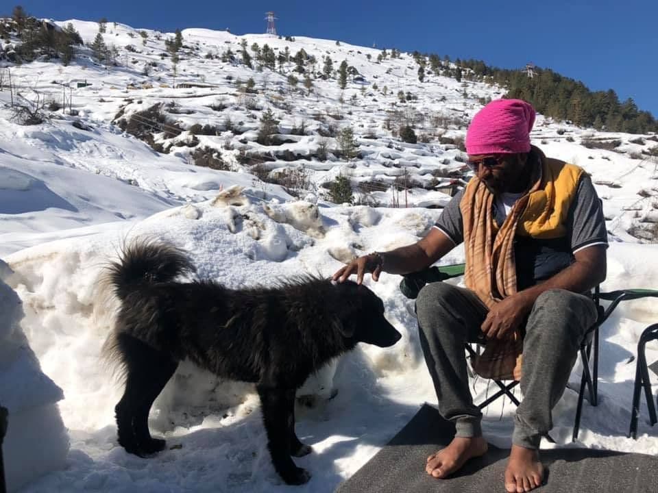 Dr. D.P. Shukla in a turban stroking a black dog in the snow