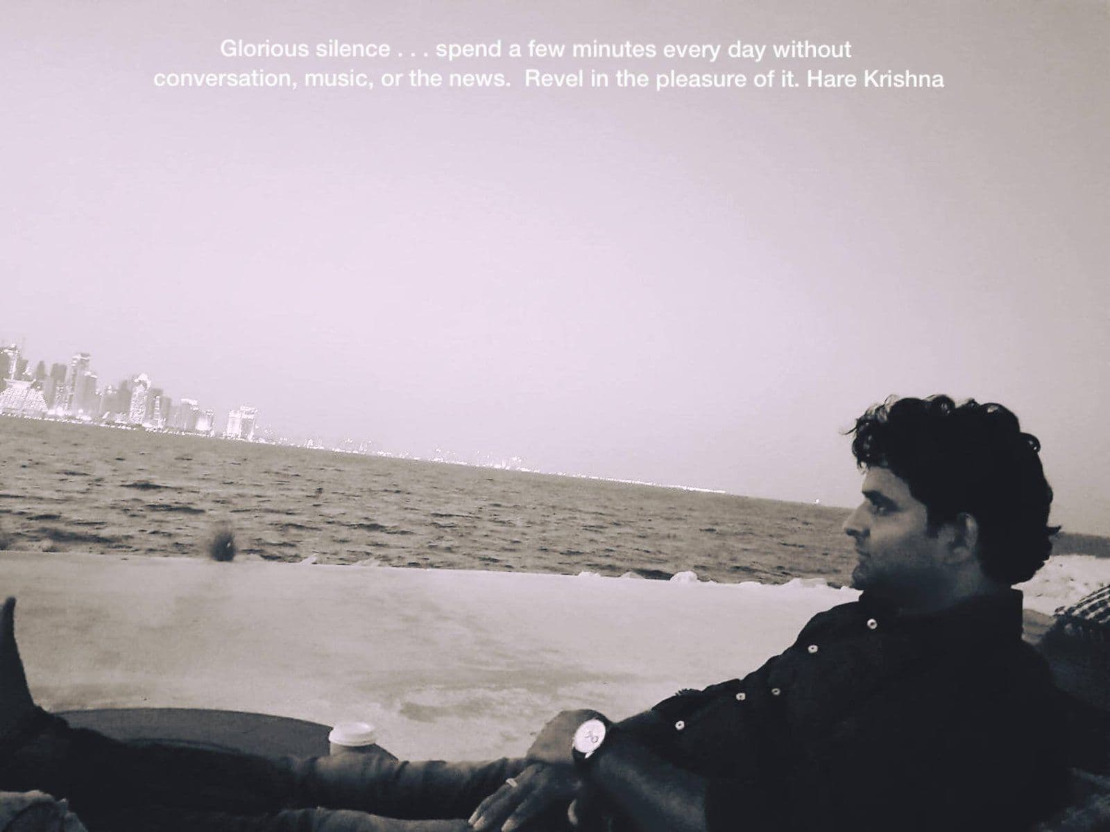 Black-and-white photo of Dr. D.P. Shukla resting by the sea, captioned about spending a few minutes each day in silence
