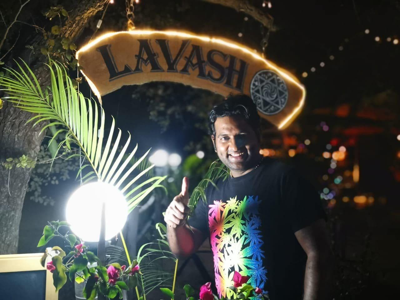 Dr. D.P. Shukla under a lit restaurant sign at night