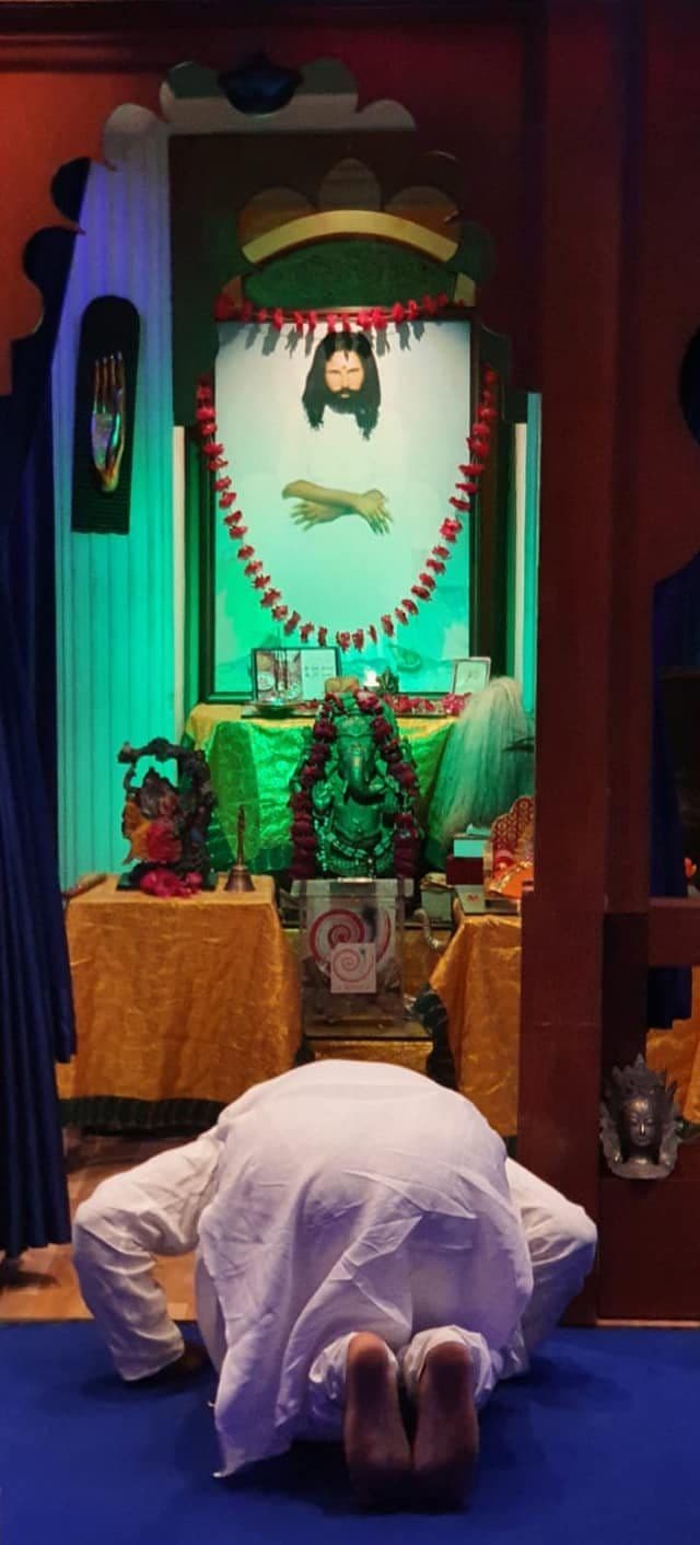 A devotee bowing before a small lit shrine