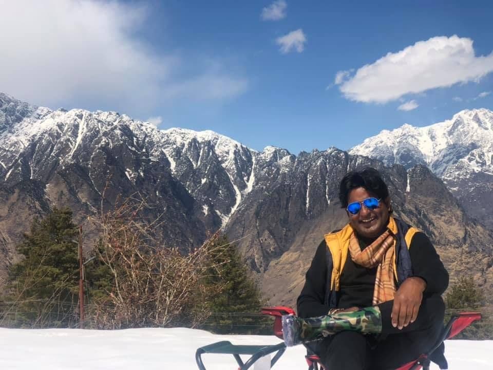 Dr. D.P. Shukla seated in the snow in front of Himalayan peaks