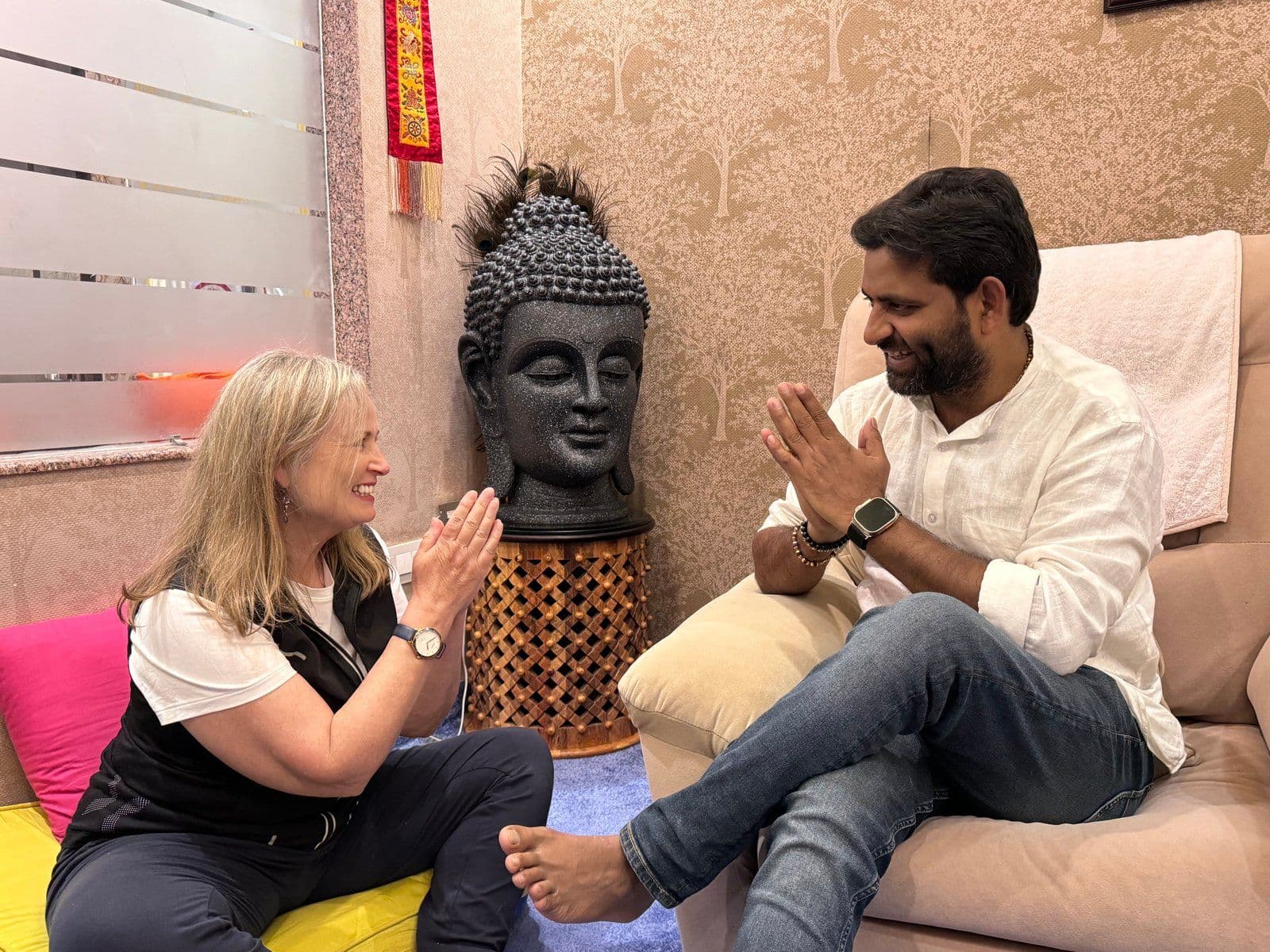 Dr. D.P. Shukla and a visitor greet each other with folded hands beside a Buddha sculpture