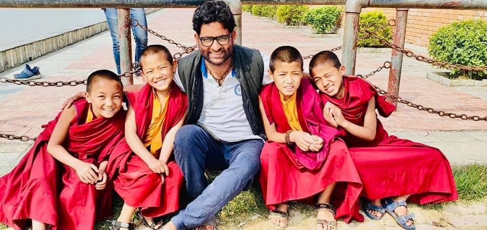 Dr. D.P. Shukla seated with young monks in red robes