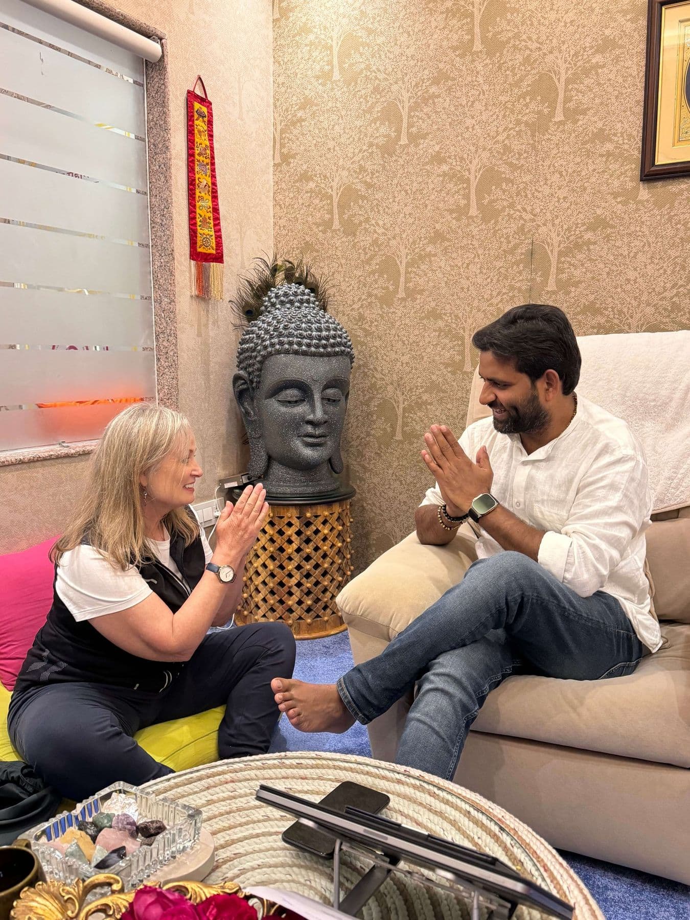 Dr. D.P. Shukla and a visitor greeting each other with folded hands beside a Buddha sculpture