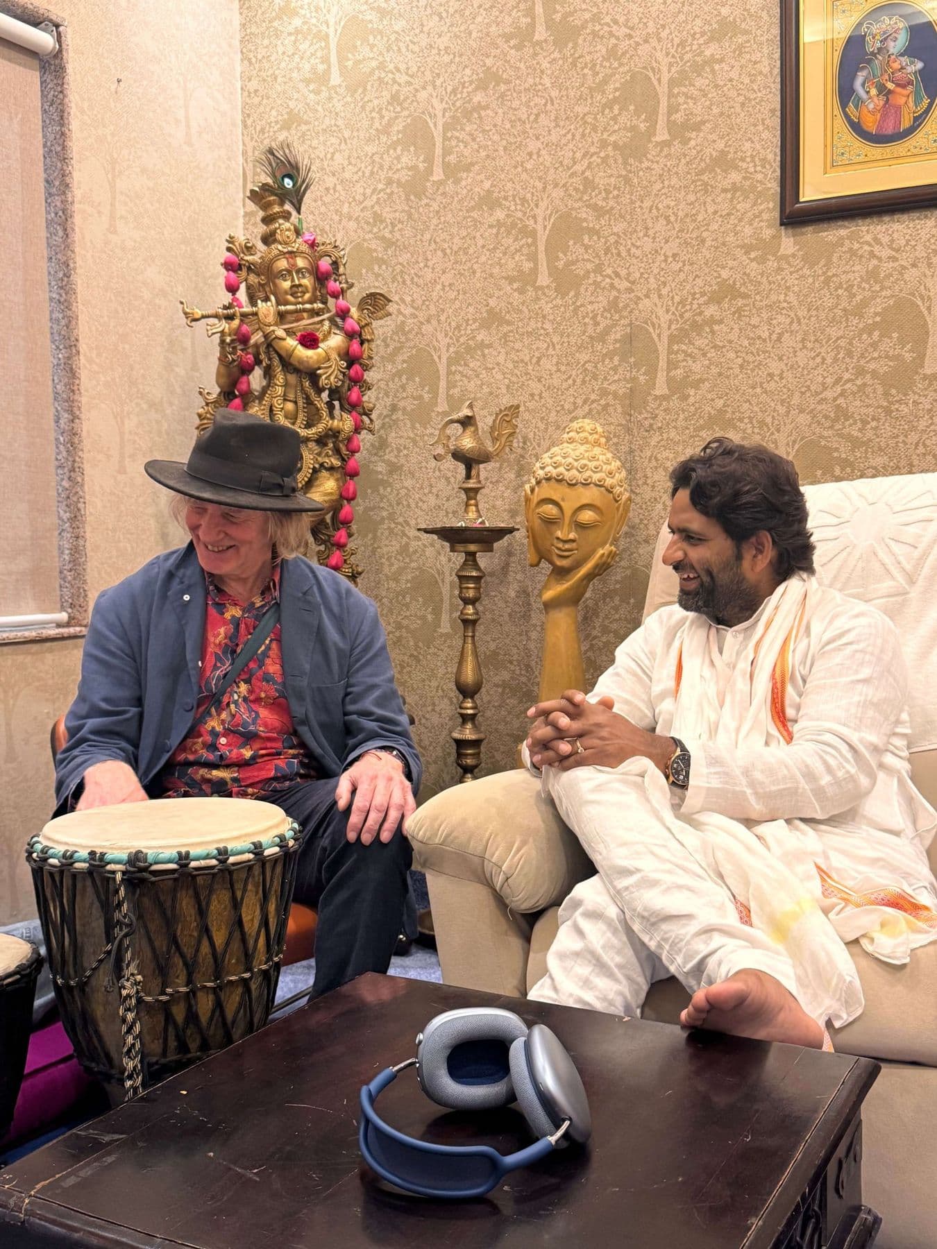 A visitor in a hat with a hand drum sitting with Dr. D.P. Shukla in the consultation room
