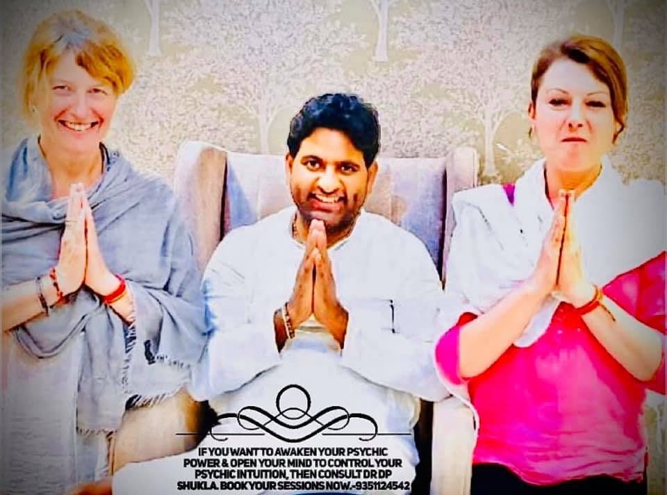 Dr. D.P. Shukla seated between two women, all with folded hands